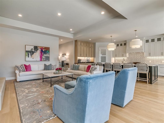 living room featuring a tray ceiling, light wood-style flooring, and recessed lighting