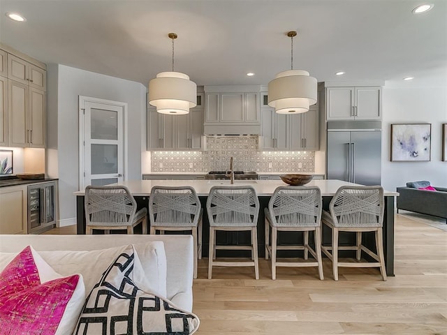 kitchen featuring custom exhaust hood, backsplash, light wood finished floors, and stainless steel built in fridge