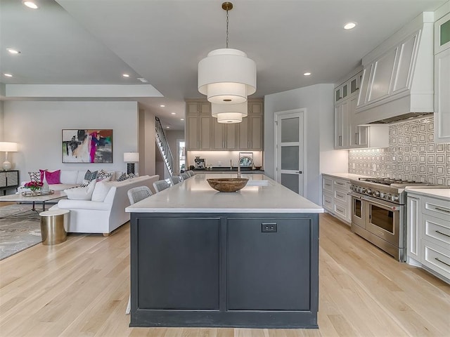 kitchen featuring custom exhaust hood, open floor plan, double oven range, and light wood-type flooring