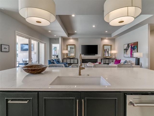 kitchen featuring dark cabinets, recessed lighting, open floor plan, and a sink