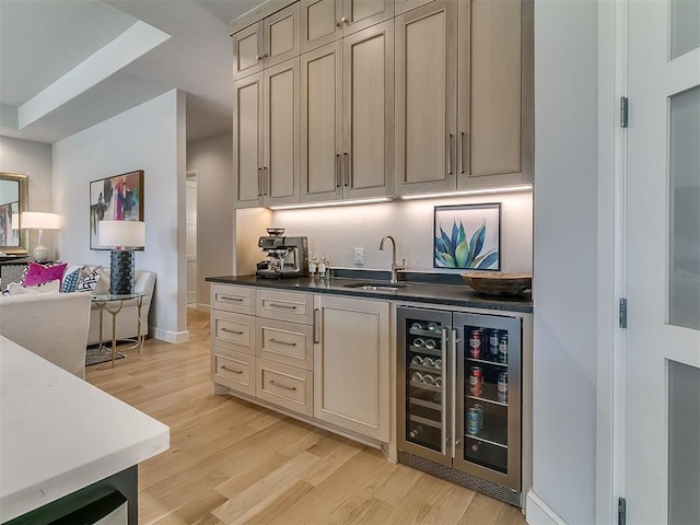 bar featuring baseboards, wine cooler, indoor wet bar, light wood-style flooring, and a sink