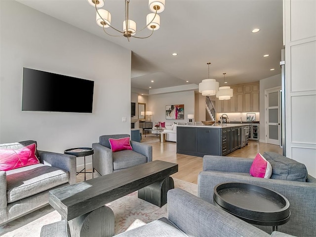 living room with wine cooler, recessed lighting, light wood-style flooring, and an inviting chandelier