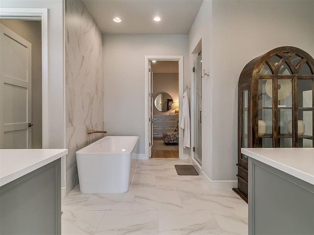 bathroom with a shower stall, recessed lighting, a soaking tub, marble finish floor, and vanity