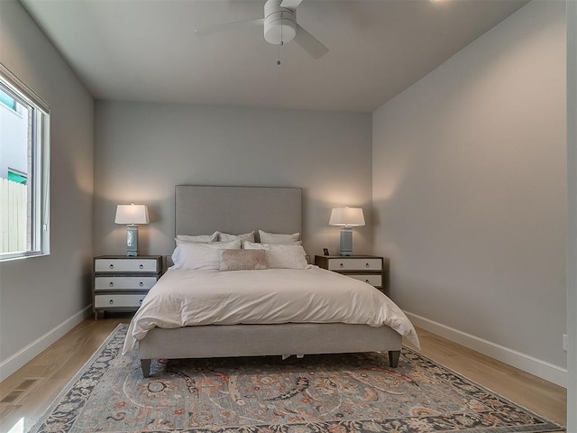 bedroom featuring light wood-style flooring, a ceiling fan, and baseboards