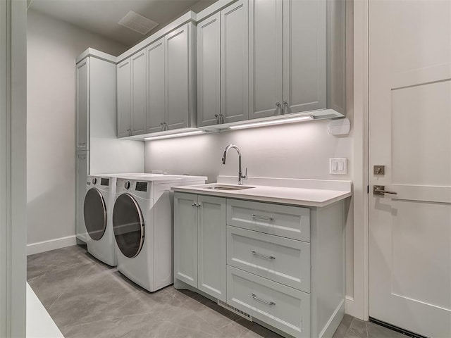 washroom with visible vents, a sink, baseboards, cabinet space, and separate washer and dryer