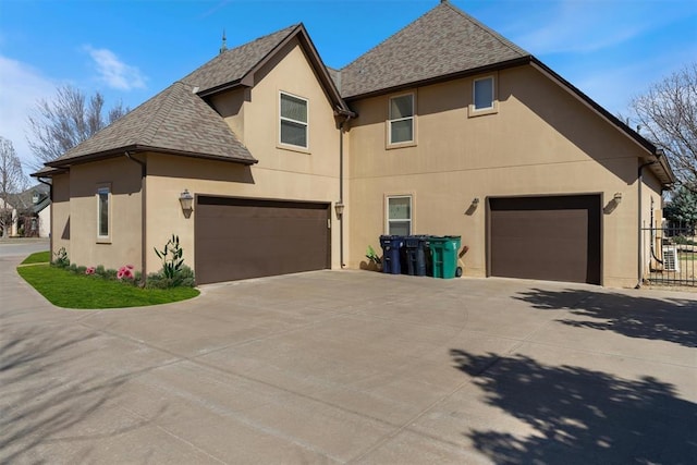 view of home's exterior featuring driveway, a shingled roof, fence, and stucco siding