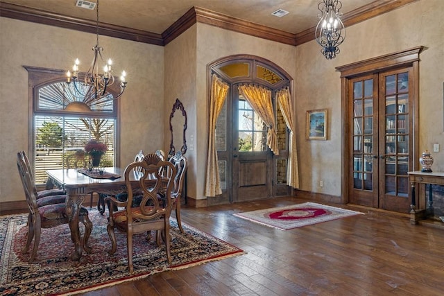 dining space featuring hardwood / wood-style flooring, a chandelier, ornamental molding, and french doors