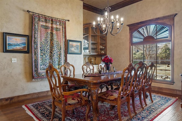 dining space featuring a textured wall, ornamental molding, a chandelier, baseboards, and hardwood / wood-style flooring