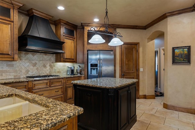 kitchen featuring arched walkways, stainless steel appliances, backsplash, custom exhaust hood, and a center island