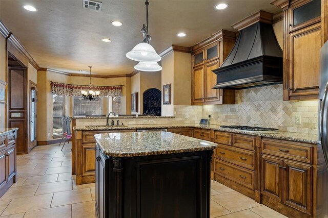 kitchen featuring a peninsula, a sink, visible vents, custom exhaust hood, and brown cabinetry