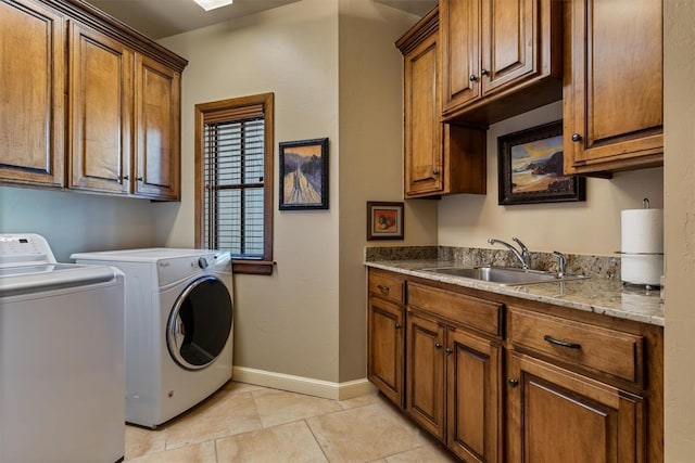 laundry room featuring washer and clothes dryer, cabinet space, light tile patterned flooring, a sink, and baseboards