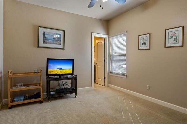 carpeted living room featuring baseboards and a ceiling fan