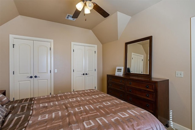 bedroom with multiple closets, visible vents, vaulted ceiling, and a ceiling fan