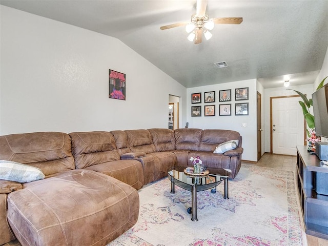 living room with light wood-type flooring, visible vents, vaulted ceiling, and a ceiling fan