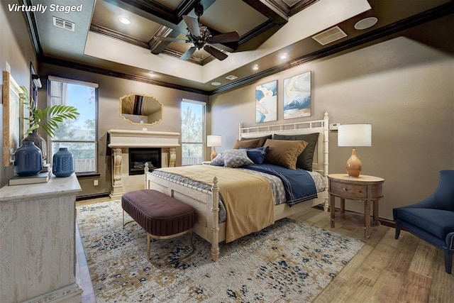 bedroom with ornamental molding, coffered ceiling, visible vents, and wood finished floors