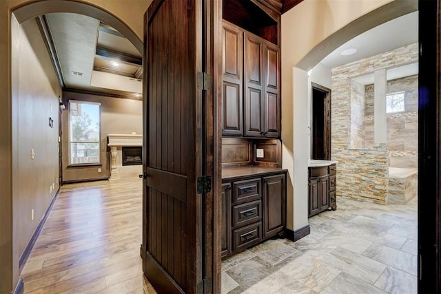 interior space with arched walkways, ornamental molding, light wood-style flooring, and baseboards