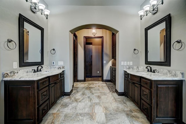 bathroom featuring baseboards, two vanities, and a sink