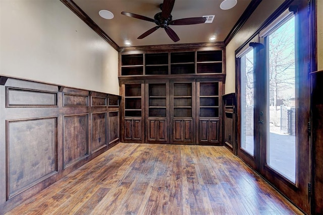 unfurnished office with wainscoting, visible vents, crown molding, and hardwood / wood-style flooring