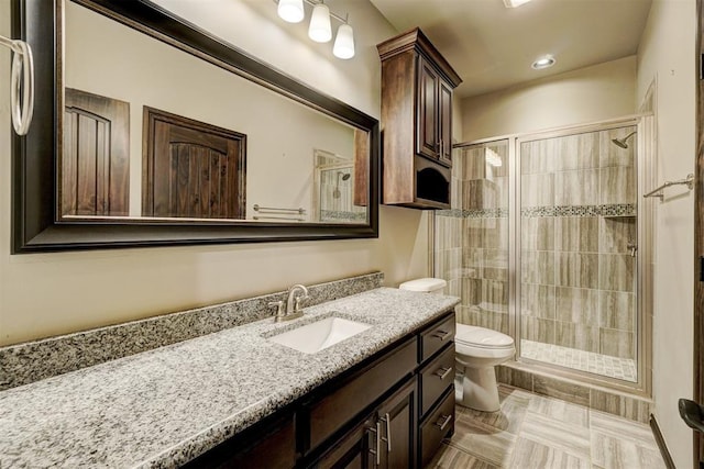 bathroom featuring vanity, a shower stall, toilet, and recessed lighting