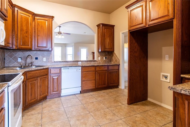 kitchen with light tile patterned floors, white appliances, a sink, a ceiling fan, and brown cabinetry