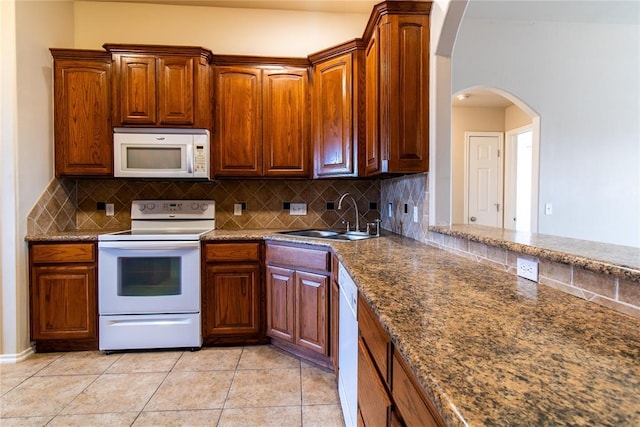 kitchen featuring white appliances, light tile patterned flooring, a sink, and tasteful backsplash