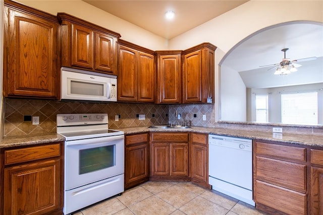 kitchen with brown cabinets, decorative backsplash, a ceiling fan, light tile patterned flooring, and white appliances