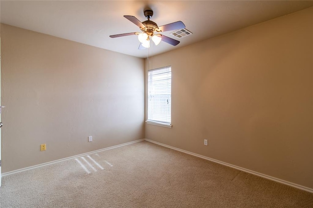 carpeted spare room with visible vents, ceiling fan, and baseboards