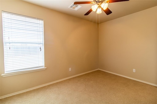 empty room with ceiling fan, visible vents, baseboards, and light colored carpet