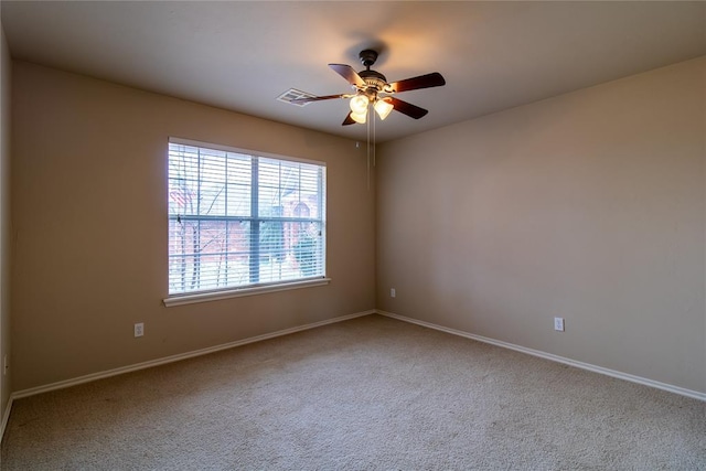 carpeted empty room with a ceiling fan, visible vents, and baseboards