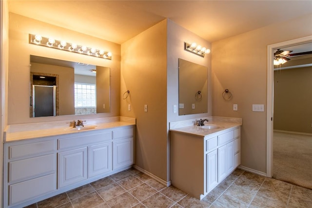 bathroom featuring ceiling fan, two vanities, a sink, and baseboards