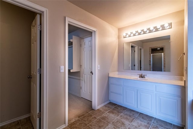 bathroom featuring tile patterned floors, an enclosed shower, baseboards, and vanity