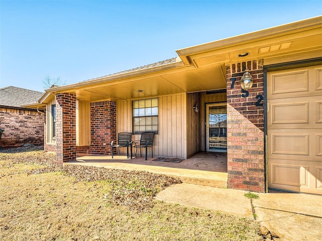 property entrance featuring covered porch, brick siding, board and batten siding, and an attached garage