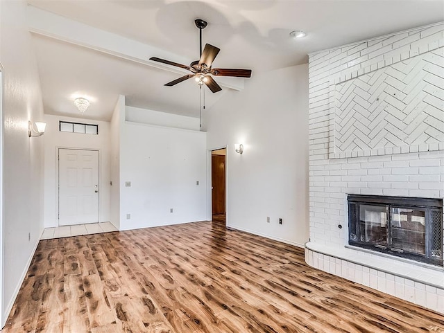 unfurnished living room featuring high vaulted ceiling, a fireplace, wood finished floors, and a ceiling fan