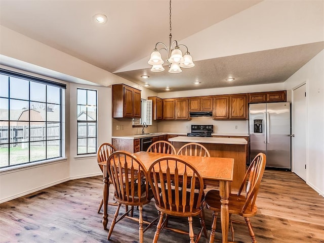 dining room featuring lofted ceiling, a notable chandelier, visible vents, and wood finished floors