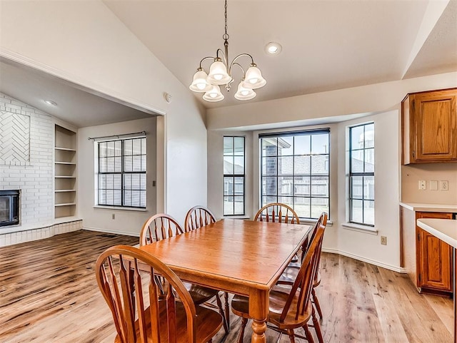 dining space with built in features, baseboards, lofted ceiling, light wood-type flooring, and a brick fireplace