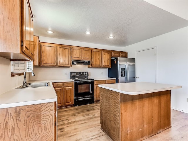 kitchen with black electric range, light wood finished floors, a sink, stainless steel fridge, and extractor fan