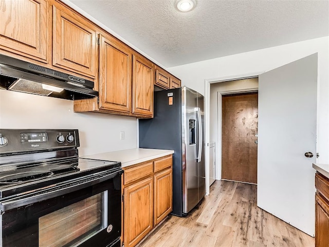 kitchen with stainless steel fridge, black range with electric stovetop, a textured ceiling, light wood-type flooring, and under cabinet range hood