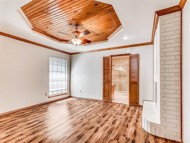 unfurnished room featuring ornamental molding, a raised ceiling, and light wood-style flooring