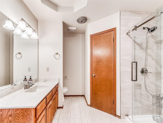 full bath featuring a stall shower, vanity, toilet, and baseboards