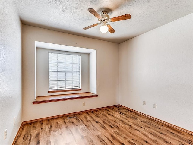 unfurnished room featuring visible vents, a textured wall, ceiling fan, a textured ceiling, and wood finished floors