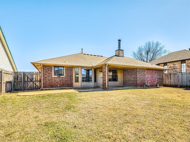 back of property with a fenced backyard, a patio, a lawn, and brick siding