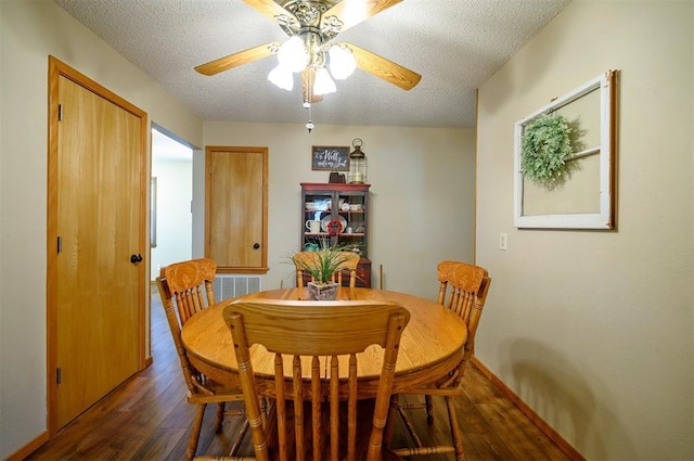 dining room featuring a textured ceiling, ceiling fan, dark wood-type flooring, and baseboards