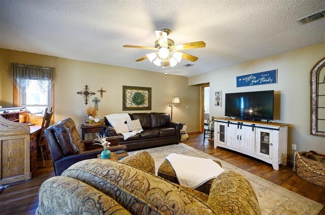 living area featuring ceiling fan, a textured ceiling, wood finished floors, visible vents, and baseboards