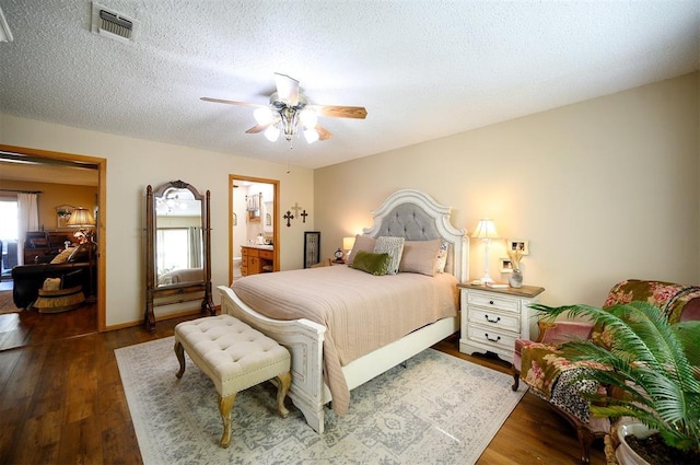 bedroom featuring a ceiling fan, visible vents, a textured ceiling, and wood finished floors