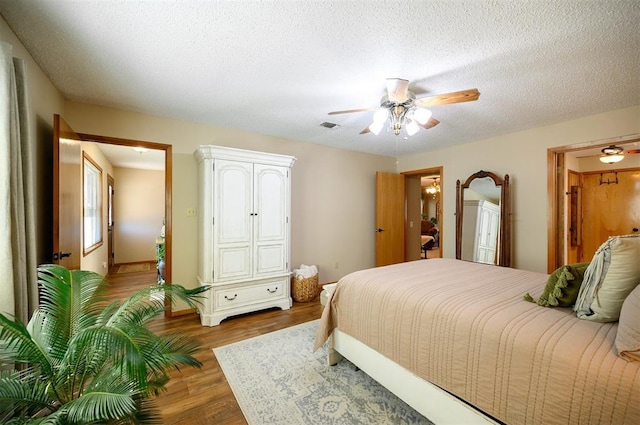 bedroom featuring a textured ceiling, wood finished floors, visible vents, and a ceiling fan