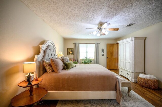 bedroom featuring a textured ceiling, ceiling fan, wood finished floors, and visible vents