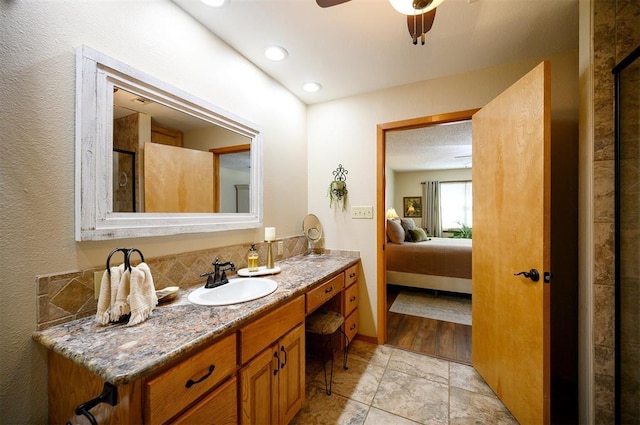 bathroom featuring ceiling fan, connected bathroom, vanity, and baseboards