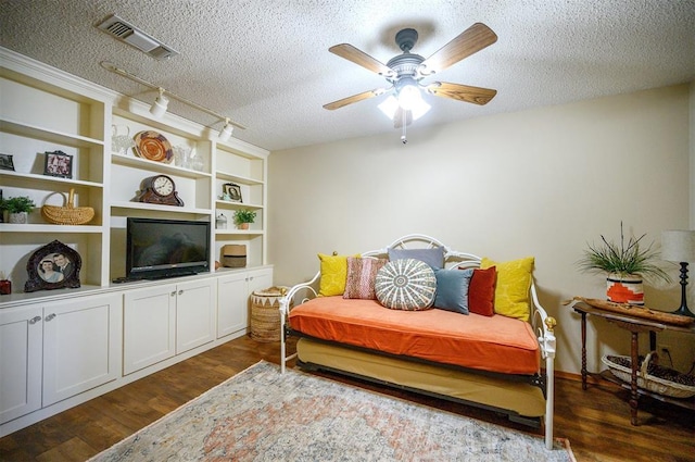 sitting room featuring visible vents, dark wood finished floors, a ceiling fan, a textured ceiling, and built in shelves