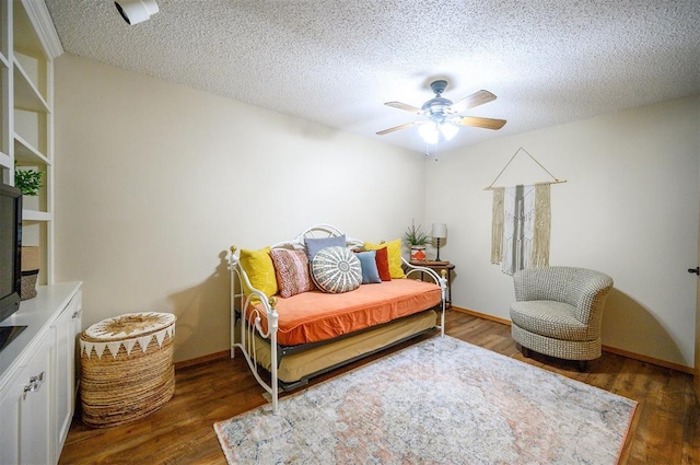 bedroom featuring a ceiling fan, a textured ceiling, baseboards, and wood finished floors