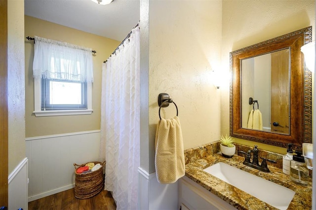 bathroom featuring a wainscoted wall, wood finished floors, and vanity